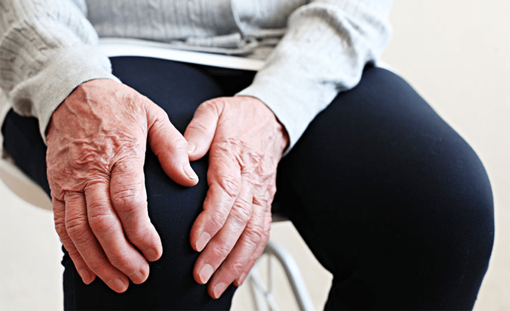 Older person's hands resting on knee.