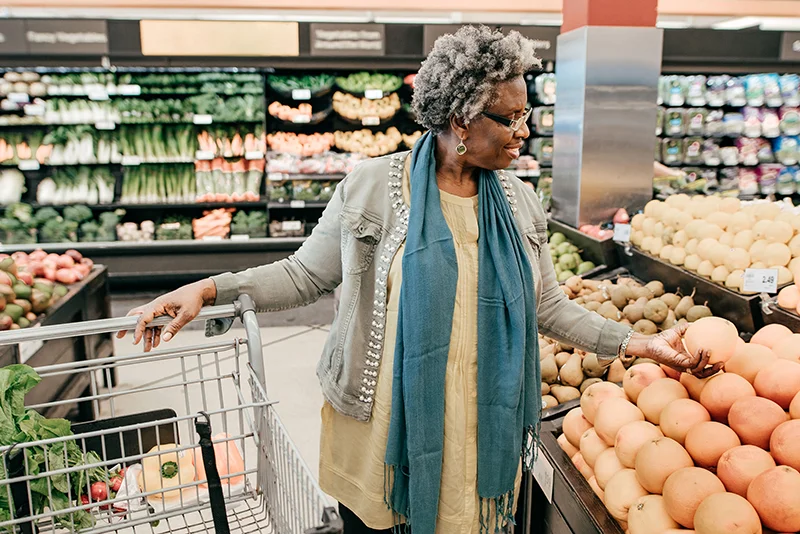 A woman selects a grapefruit in a grocery store.
