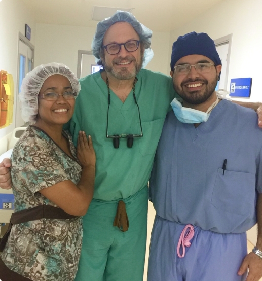 Three posing healthcare professionals in a hospital setting, wearing scrubs and surgical gear.
