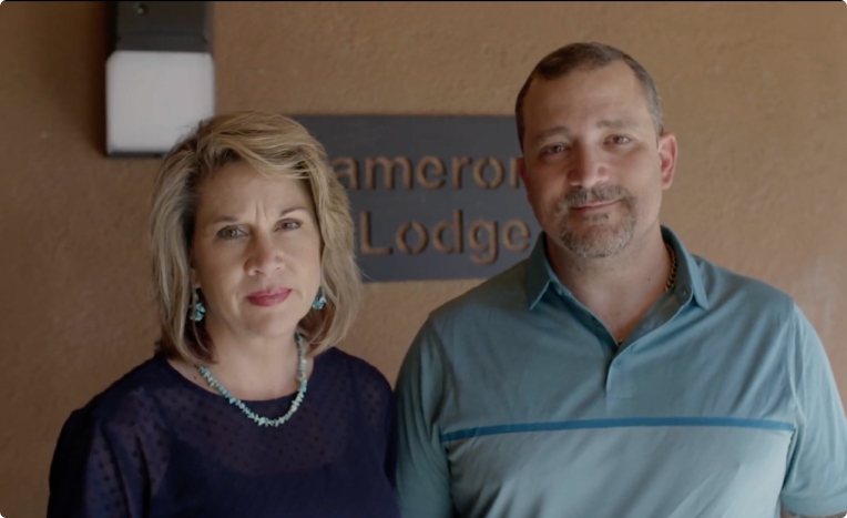 Couple stands by Cameron Lodge sign.