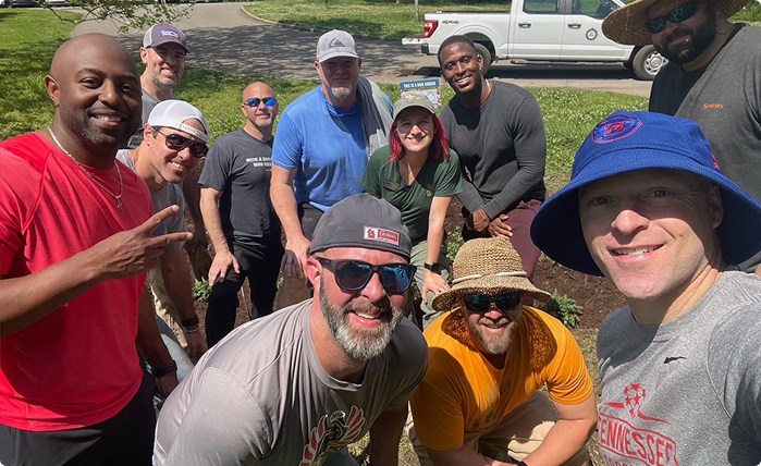 Smiling group of volunteers outdoors, posing during a community service project.